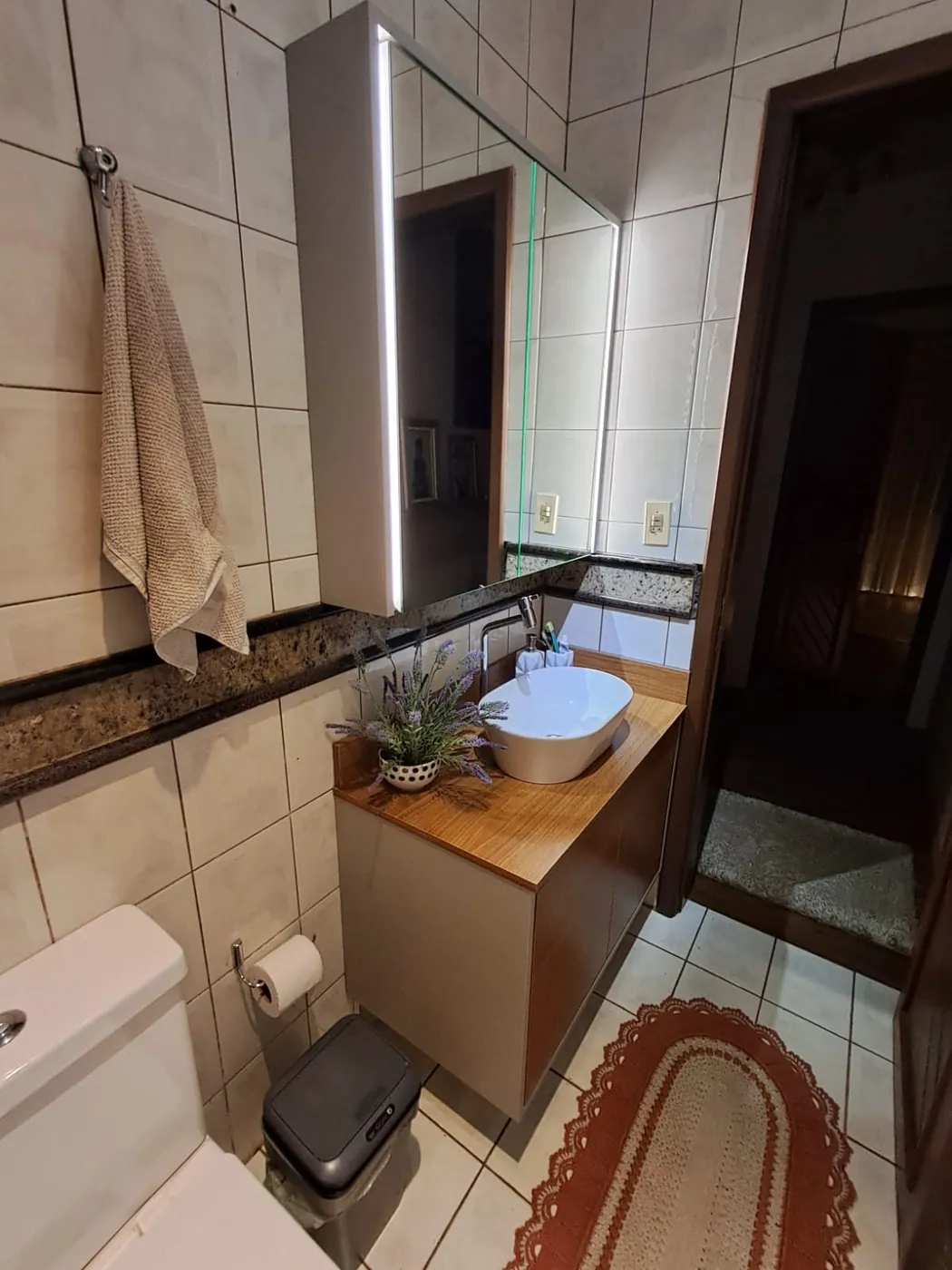 Banheiro sob medida amadeirado com LED vertical integrado no armário aéreo